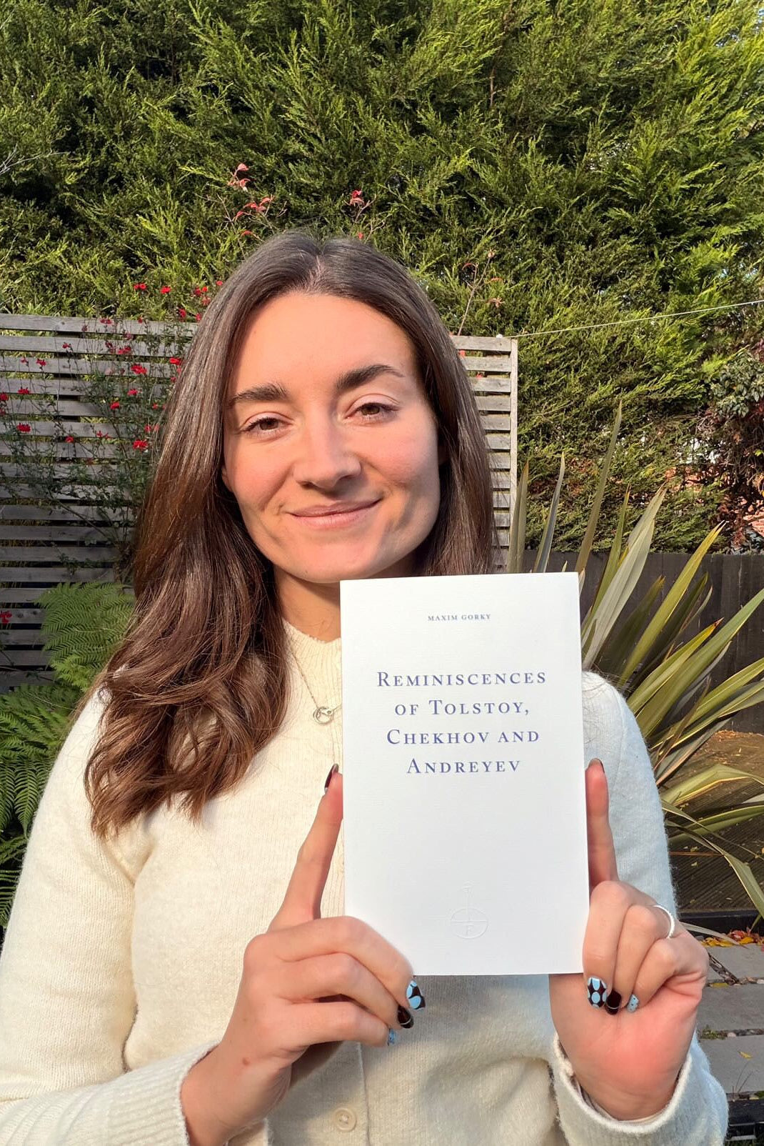 Person holding a book titled 'Reminiscences of Tolstoy, Chekhov and Andreyev' outdoors.